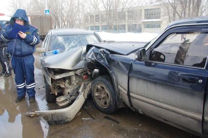 У разбитых автомобилей ВАЗ и Волга стоит полицейский и записывает замеры, Саратов, 8 февраля 2011 года