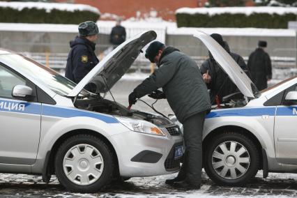 Милиционеры полицейские ремонтируют авто на Красной площади, Москва, 5 марта 2011 года.