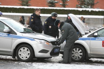 Милиционеры полицейские ремонтируют авто на Красной площади, Москва, 5 марта 2011 года.