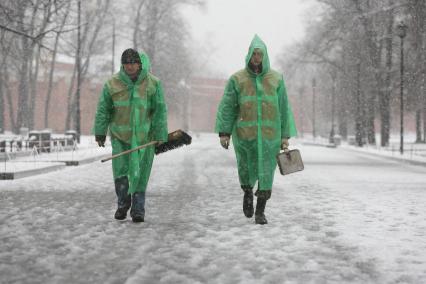 В начале апреля неожиданно выпал снег, гастарбайтеры в зеленых плащах- накидках идут на уборку города, Москва, 9 апреля 2011 года