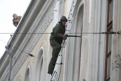 Рабочий на лестнице моет из шланга фасад дома, Москва, 10 апреля 2011 года