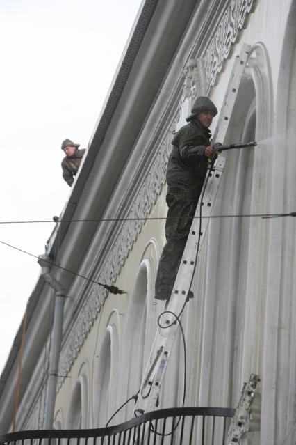 Рабочий на лестнице моет из шланга фасад дома, Москва, 10 апреля 2011 года