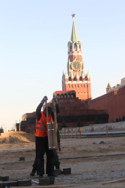 04 апреля 2011 г. Россия, Москва. Работы по ремонту и перекладка брусчатки на Красной площади. На заднем плане Спасская башня.