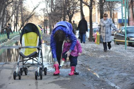 04 апреля 2011 г. Россия, Москва. Дети и их родители. Лужа на тротуаре.