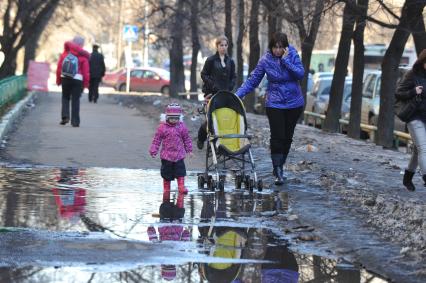 04 апреля 2011 г. Россия, Москва. Дети и их родители. Лужа на тротуаре.