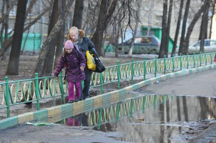 04 апреля 2011 г. Россия, Москва. Дети и их родители. Лужа на тротуаре.