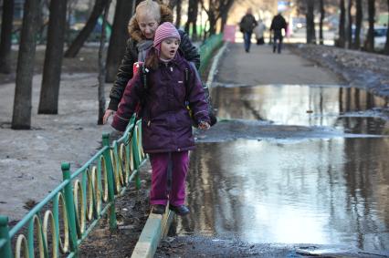 04 апреля 2011 г. Россия, Москва. Дети и их родители. Лужа на тротуаре.