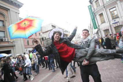 Парень размахивает зонтом, лежа на руках у друга, Москва, 10 апреля 2011 года