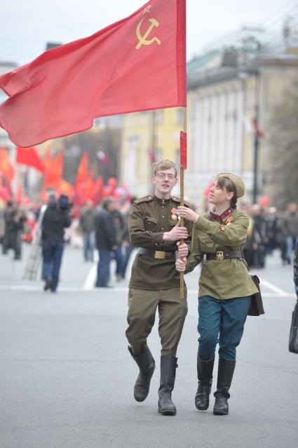 Парень и девушка в военной форме идут по улице и несут красный флаг, Москва, 1 мая 2011 года