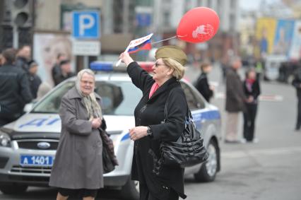 Женщина в военной пилотке с флажками в руках танцует на улице города, Москва, 1 мая 2011 года