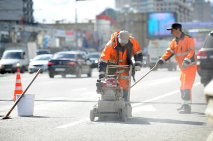 Гастарбайтеры занимаются уборкой проезжей части дороги на Новом Арбате, Москва, 19 апреля 2011 года