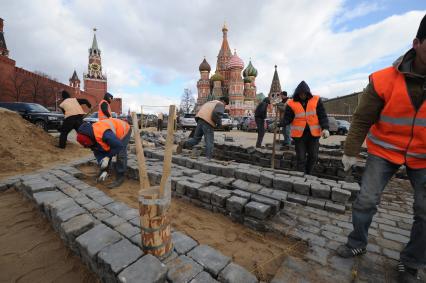 20 апреля 2011 год.Россия, Москва. Работы по ремонту и перекладка брусчатки на Красной площади. На заднем плане Храм Василия Блаженного и Спасская башня (слева).