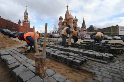 20 апреля 2011 год.Россия, Москва. Работы по ремонту и перекладка брусчатки на Красной площади. На заднем плане Храм Василия Блаженного и Спасская башня (слева).