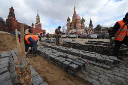 20 апреля 2011 год.Россия, Москва. Работы по ремонту и перекладка брусчатки на Красной площади. На заднем плане Храм Василия Блаженного и Спасская башня (слева).