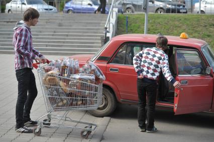 Молодые люди в тележке из супермаркета везут упаковки пива к такси, Иваново, 26 июня 2011 года