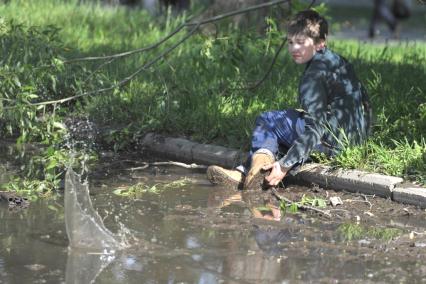 Мальчик сидит на бордюре, свесив ноги в лужу, Иваново, 27 июня 2011 года