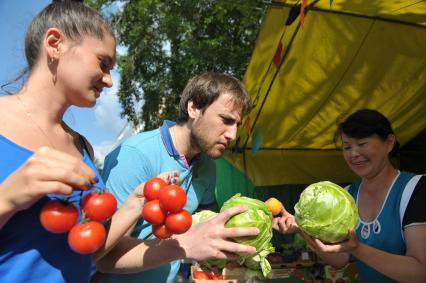 Молодой человек и девушка с помидорами и свежей капустой в руках,  Москва,10 июня 2011 года