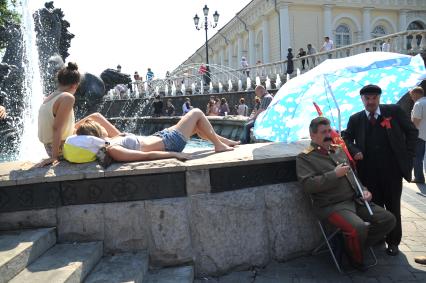 Около здания Манежа, на Манежной площади две девушки отдыхают около фонтана, рядом под зонтом отдыхают два артиста переодетые в Стаилна и Ленина. 2 июня 2011 года.