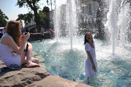 Молодая девушка позирует фотографу стоя в фонтане. 2 июня 2011 года.