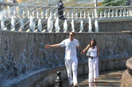 Мужчина и женщина держась за руки идут около фонтана. 2 июня 2011 года.