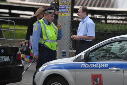 Полицейский у машины с надписью полиция разговаривает с мужчиной в костюме, Москва, 22 июня 2011 года