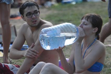 Девушка пьет воду из огромной бутылки, Москва, 3 июля  2011 года