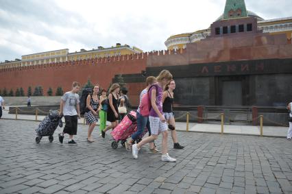 Туристы с чемоданами идут по Красной площади, Москва, 14 июля 2011 года.