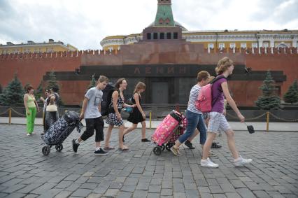 Туристы с чемоданами идут по Красной площади, Москва, 14 июля 2011 года.