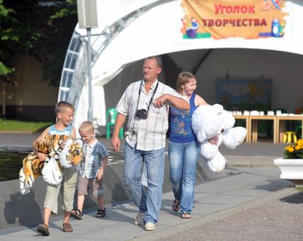 Семья из четпрех человек идет с выигранными в аттракционах игрушками в Парке Горького, 13 июля 2011 года, Москва