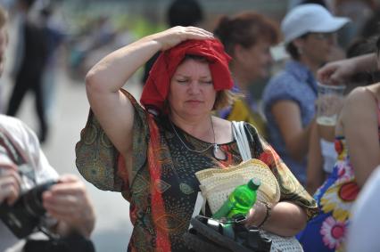 Женщина накрыла голову майкой, спасаясь от жары, Москва, 16 июля 2011 года.