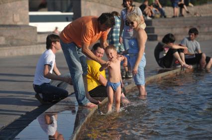 Родители купают ребенка в фонтане в жару, Москва, 16 июля 2011 года.