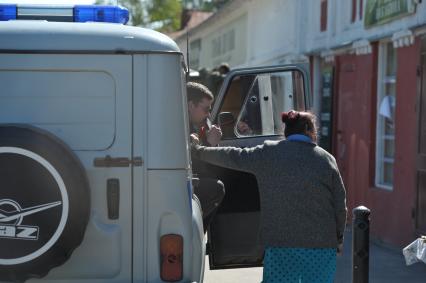 Участковый полицейский- милиционер у служебной машины разговаривает с женщиной, Плес, 28 мая 2011 года.