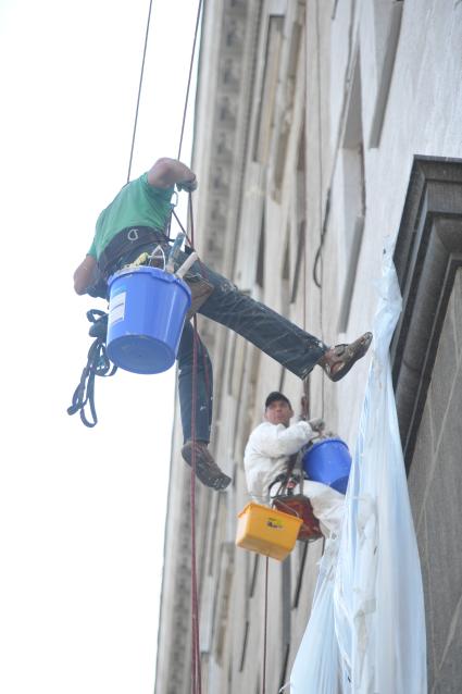 Гастарбайтеры красят фасад дома, Москва, 28 июля 2011 года.