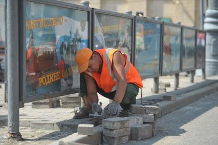 Гастарбайтеры укладывают плитку на тротуар, Москва, 28 июля 2011 года.