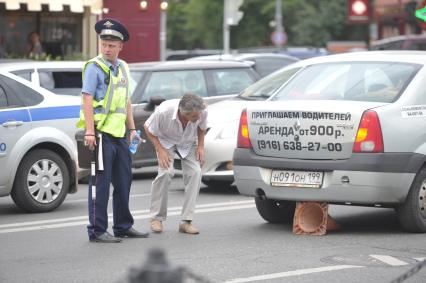 Полицейский беседует с нарушителем- водитель наехал на предупреждающий о ремонтных дорогах знак, Москва, 26 июля 2011 года.