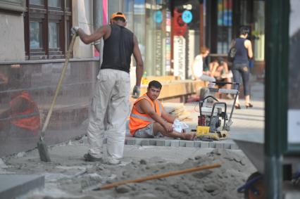 Гастарбайтеры занимаются укладкой плитки на тротуаре, Москва, 27 июля 2011 года.