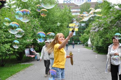 Девочка на улице пускает большие мыльные пузыри. 1 июня 2011 года.