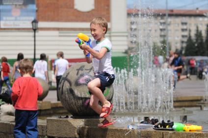 Ребенок, мальчик с водным пистолетом играет возле фонтана. 2 июля 2011 года. Новосибирск.