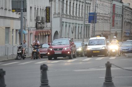 Скутеры и мопеды на дороге города среди машин, Москва, 26 июля 2011 года.