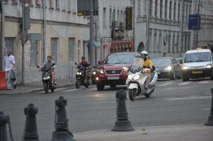 Скутеры и мопеды на дороге города среди машин, Москва, 26 июля 2011 года.