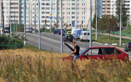 Мужчина стоит в поле около новостройки. Поломка машины. 17 августа 2011 года.