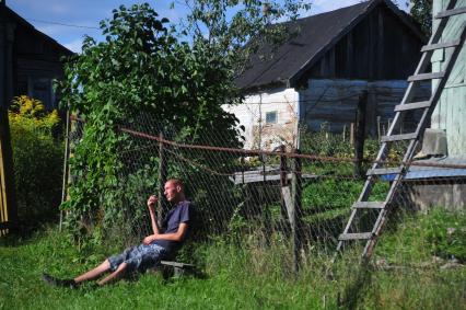 Сельский житель. На снимке: молодой человек сидит на лавочке у забора. 25 августа  2011 года.