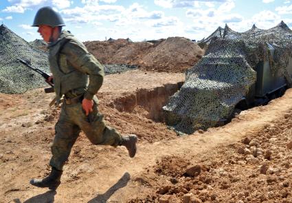 На снимке: Камуфлирование. Содат пробегает мимо закамуфлированной техники. Учения ЦЕНТР-2011 на полигоне КАПУСТИН ЯР_. 20 сентября 2011 года.