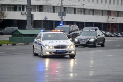 Автомобили с проблесковыми маячками  движутся по дороге в сопровождении машины ДПС. 22 сентября  2011 года.