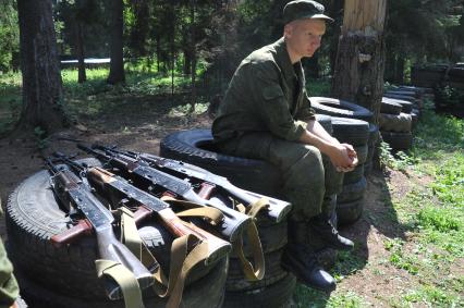 Оружие. Автоматы. Солдат сидит на покрышках от автомобиля. Учения. Военная подготовка. Военно-полевые сборы. 17 июля 2011г.