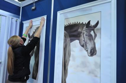 Международная конная выставка ЭКВИРОС. На снимке: девушка размещает фотографии лошадей. 5 октября 2011 года.