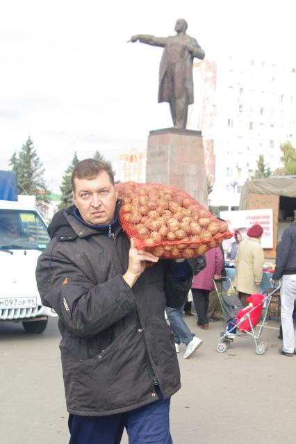 Мужчина несет мешок  с картошкой на овощной ярмарке, 3 сентября  2011 года.