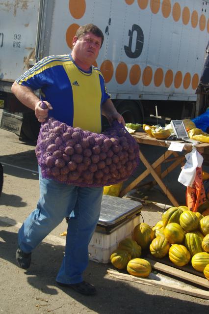 Мужчина несет мешок с картошкой на овощной ярмарке, 3 сентября 2011 года.