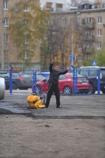 Нелегальная автомобильная стоянка. Стоянка во дворе домов. Мужчина с ручным асфальтоукладчиком 24 октября 2011 г.