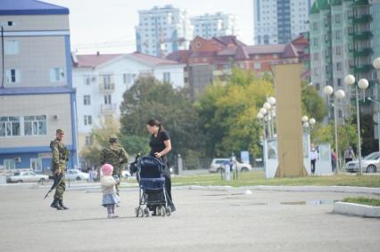 Виды Грозного. На снимке: женщина с ребенком и военные на одной из улиц Грозного.  5 октября 2011 года.